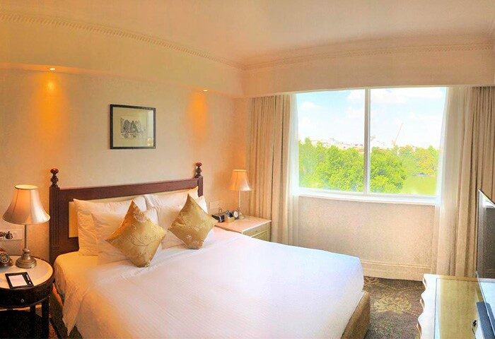 Apricot Hotel Room. Gay-friendly hotel bedroom with a double bed, pillows, lamps, and a window with a park view. Comfortable stay.