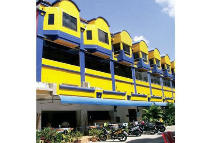 Exterior of Aquarius Gay Guesthouse and Sauna, a gay-friendly hotel. Yellow and blue building with motorbikes parked outside. Gay travel lodging.