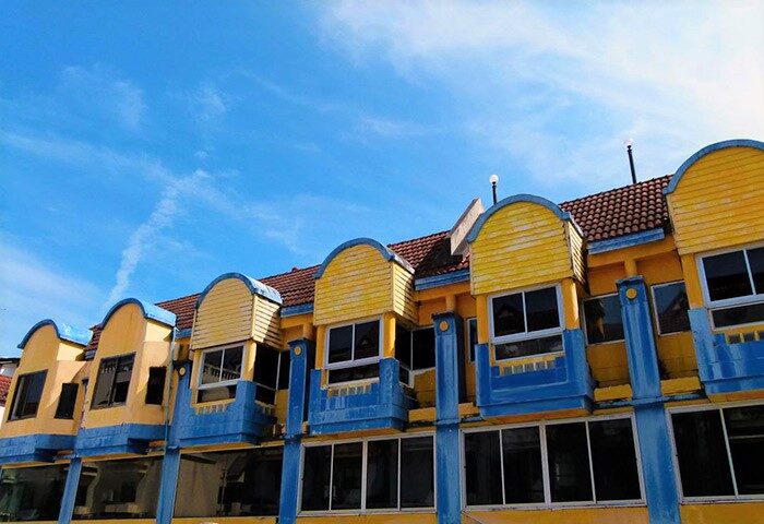 Aquarius Gay Guesthouse and Sauna, a gay-friendly hotel. Exterior view of the yellow and blue building under a bright blue sky. Gay men travel lodging.