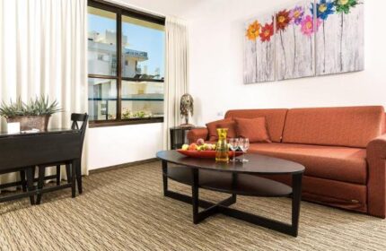 Arbel Suites Hotel room. Gay-friendly hotel suite with couch, table, and colorful flower art. Modern interior design for LGBTQ+ travelers.