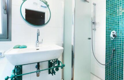 Arbel Suites Hotel gay-friendly bathroom: Sink with a fancy mirror, and a shower with green tiles. A modern design for gay travelers.
