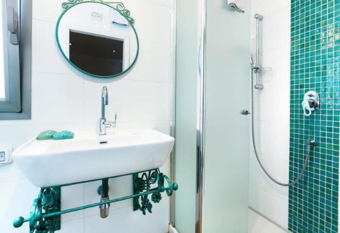 Arbel Suites Hotel gay-friendly bathroom: Sink with a fancy mirror, and a shower with green tiles. A modern design for gay travelers.