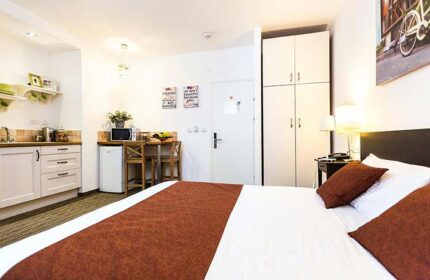 Arbel Suites Hotel room. Gay-friendly hotel suite with bed, kitchenette, table, and closet. Modern design for gay men travel.