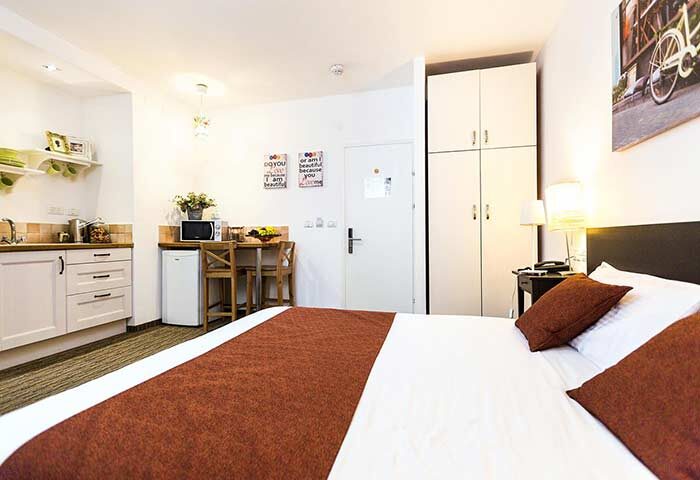 Arbel Suites Hotel room. Gay-friendly hotel suite with bed, kitchenette, table, and closet. Modern design for gay men travel.