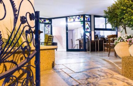 Entrance to Arbel Suites Hotel, a gay-friendly hotel. Ornate iron gate, stone path, and glass doors. Comfortable, welcoming space.