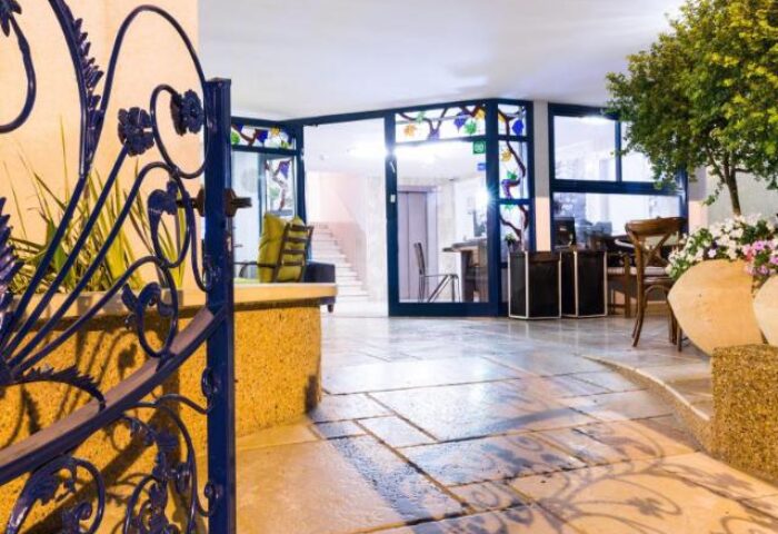 Entrance to Arbel Suites Hotel, a gay-friendly hotel. Ornate iron gate, stone path, and glass doors. Comfortable, welcoming space.