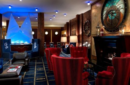 Argonaut Hotel's nautical-themed lobby. This gay-friendly hotel has a seating area with red chairs, a fireplace, and a large clock.