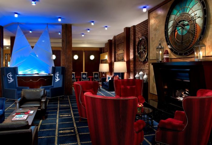 Argonaut Hotel's nautical-themed lobby. This gay-friendly hotel has a seating area with red chairs, a fireplace, and a large clock.