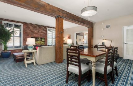 Argonaut Hotel's gay-friendly suite. Living area with brick wall, sofa, and TV. Dining table with chairs. Bedroom view. Stylish, comfortable.