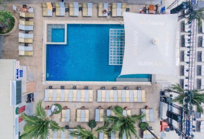 Aerial view of Ark Bar Beach Resort pool and lounge area. Gay-friendly hotel with sunbeds and palm trees. Perfect for gay travel.