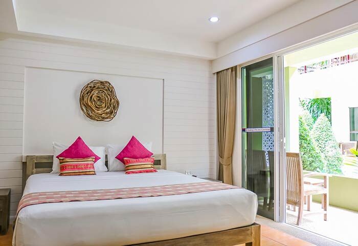 Ark Bar Beach Resort gay-friendly hotel room. White linens, pink pillows, and a balcony with a chair. Perfect for gay travel.