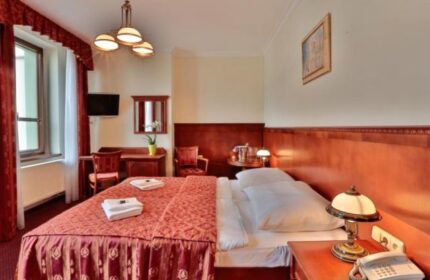 Arkada Hotel Praha room. Gay-friendly hotel in Prague features a comfortable bed, desk, and warm decor. Ideal for gay men travelers.