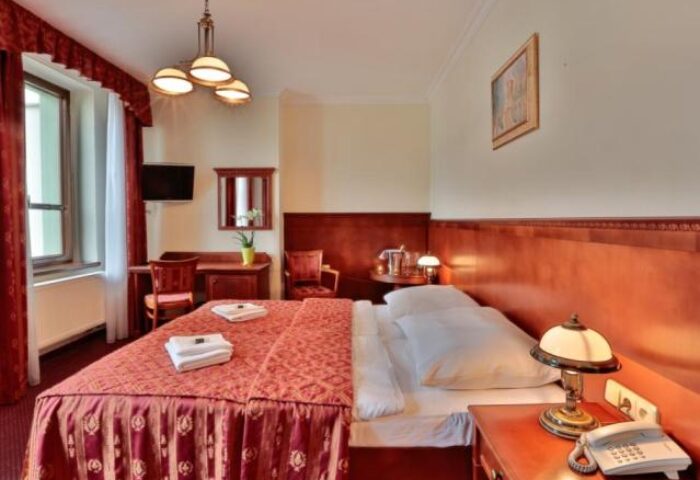 Arkada Hotel Praha room. Gay-friendly hotel in Prague features a comfortable bed, desk, and warm decor. Ideal for gay men travelers.