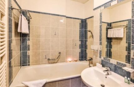Bathroom interior at Arkada Hotel Praha, a gay-friendly hotel. Features a bathtub, sink, and tiled walls. Ideal accommodation for gay travelers.