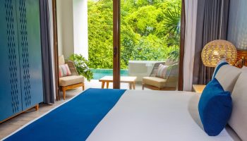Armony Resort & Spa MGallery adults-only room. Balcony view, pool, and lush greenery. Gay-friendly hotel for all-inclusive travel. Relaxing getaway.