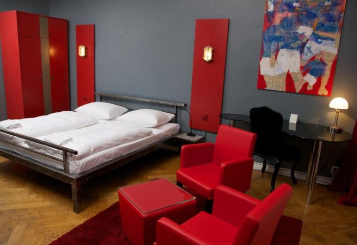 ArtHotel Connection gay-friendly hotel room. Modern design with a bed, red accents, and an abstract painting. Pet-friendly option.