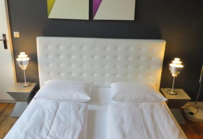 ArtHotel Connection gay-friendly hotel room. Twin beds with white linens, bedside lamps, and art of the Berlin TV Tower. Pet-friendly.
