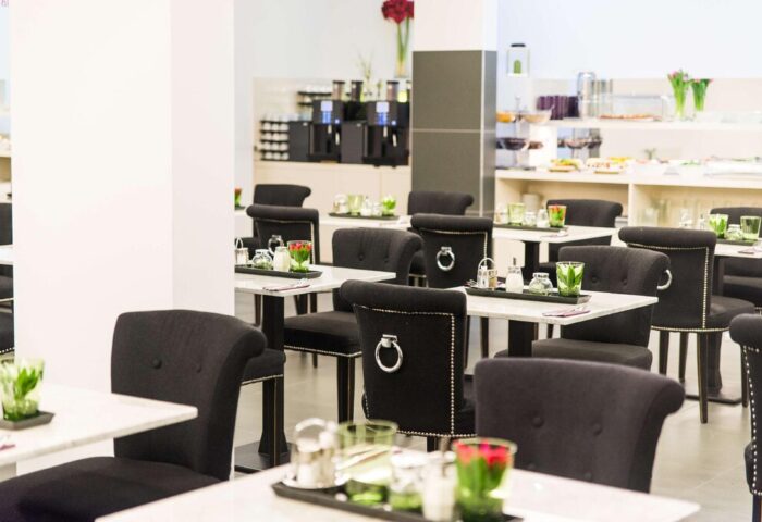 Arthotel ANA Boutique Six dining area. Gay-friendly hotel with black chairs, marble tables, and breakfast buffet. Modern design for gay men travelers.