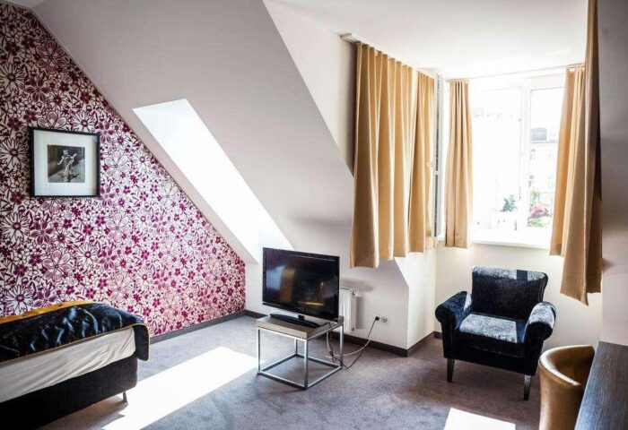 Arthotel ANA Boutique Six room. Gay-friendly hotel room with floral wallpaper, TV, chair, and window. Modern decor for gay travel.