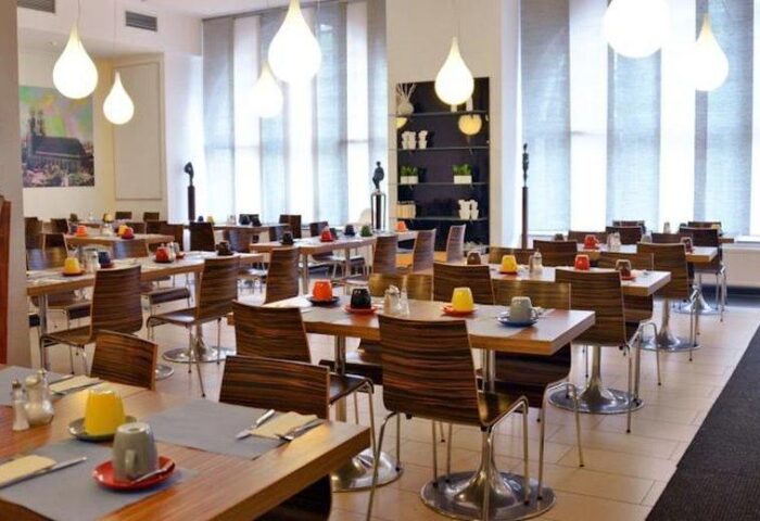 Arthotel Munich's dining area. The gay-friendly hotel features tables set for breakfast with colorful cups. Modern lighting and decor.