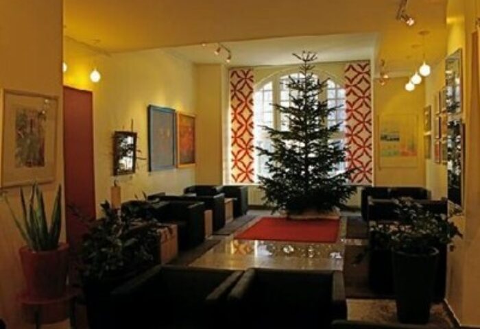 Arthotel Munich lobby area with Christmas tree. Gay-friendly hotel with art, seating, and natural light. A welcoming space for gay travelers.