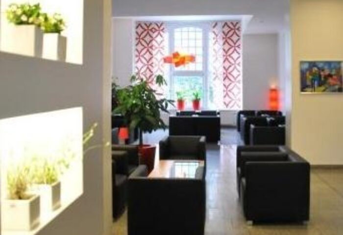 Arthotel Munich lobby seating area. Gay-friendly hotel with modern decor, plants, and comfortable chairs. A welcoming space for gay travelers.
