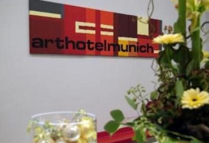 Arthotel Munich lobby decor. Modern art sign above floral arrangement. Gay-friendly hotel in Munich, Germany for gay men's travel.