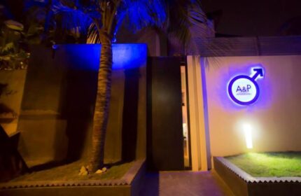 Entrance to Arthur&Paul, a gay-friendly men-only hotel. A&P logo with male symbol. Palm tree, modern design, and welcoming ambiance. Night shot.
