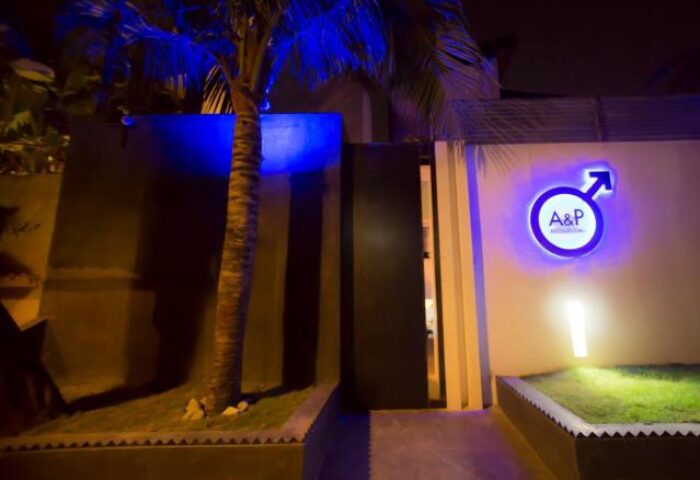 Entrance to Arthur&Paul, a gay-friendly men-only hotel. A&P logo with male symbol. Palm tree, modern design, and welcoming ambiance. Night shot.