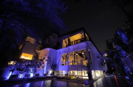 Arthur&Paul Men Only Hotel exterior at night. Gay-friendly hotel with a pool. Modern architecture, illuminated with blue lights. Men only travel.