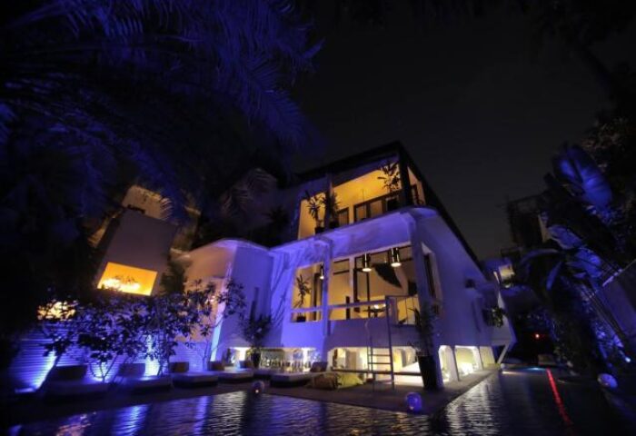 Arthur&Paul Men Only Hotel exterior at night. Gay-friendly hotel with a pool. Modern architecture, illuminated with blue lights. Men only travel.