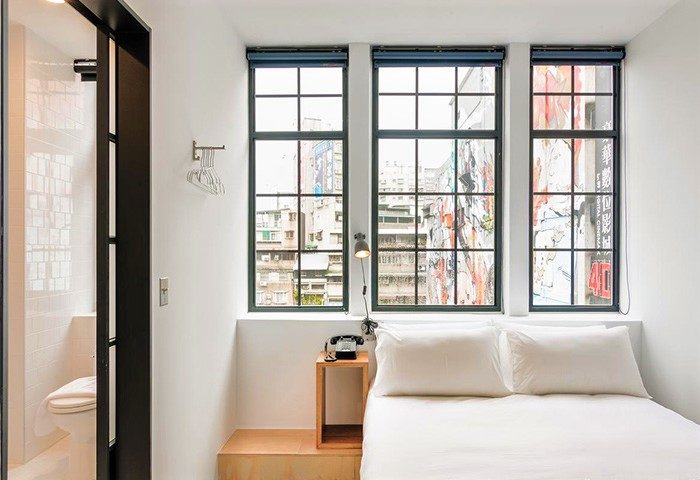 Art'otel Ximending Taipei room. Gay-friendly hotel with white bedding, three large windows, and a view of the city. Modern, clean design.