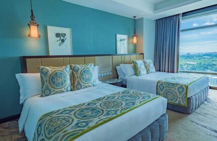 Ascott Makati gay-friendly hotel room with two beds, blue accent wall, city view. Upscale accommodations for gay travelers in Makati, Philippines.