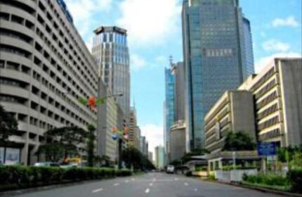Street view of Ascott Makati, a gay-friendly hotel in Makati, Philippines. Tall buildings line the street under a blue sky. Urban travel destination.