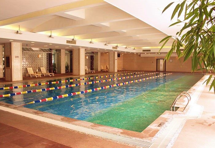 Indoor pool at Asia Hotel, a gay-friendly hotel. The pool has lane markers and lounge chairs. Asia Hotel is a great place to stay.