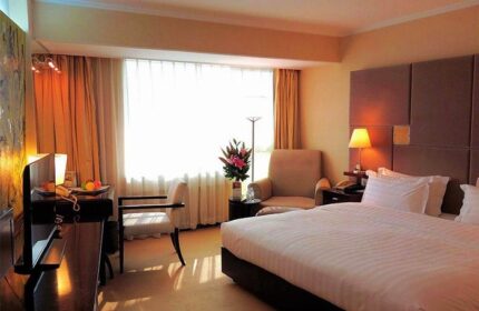 Asia Hotel room interior, a gay-friendly hotel. Features a bed, chair, desk, and window. Ideal for gay men seeking comfortable travel accommodations.