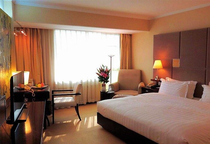Asia Hotel room interior, a gay-friendly hotel. Features a bed, chair, desk, and window. Ideal for gay men seeking comfortable travel accommodations.