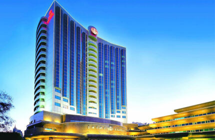 Asia Hotel exterior. Gay-friendly hotel with modern architecture, blue glass windows, and illuminated entrance. Gay travel in Asia.