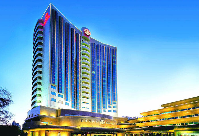 Asia Hotel exterior. Gay-friendly hotel with modern architecture, blue glass windows, and illuminated entrance. Gay travel in Asia.