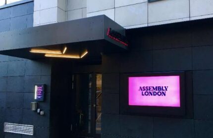 Assembly Hotel entrance. Gay-friendly hotel in London. Modern facade with a pink sign. Great choice for gay men travel.