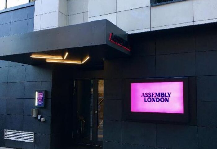 Assembly Hotel entrance. Gay-friendly hotel in London. Modern facade with a pink sign. Great choice for gay men travel.