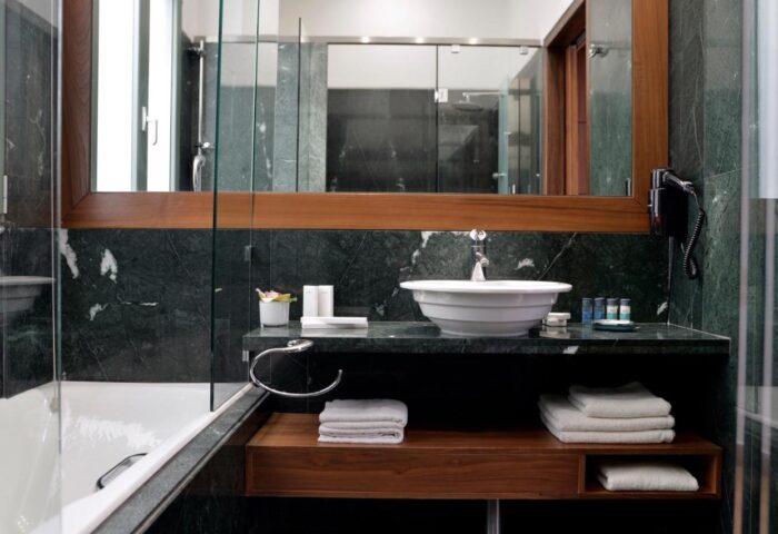 Athenaeum Eridanus Luxury Hotel's bathroom. Gay-friendly hotel featuring a marble countertop, white sink, and towels. Upscale design for gay travelers.