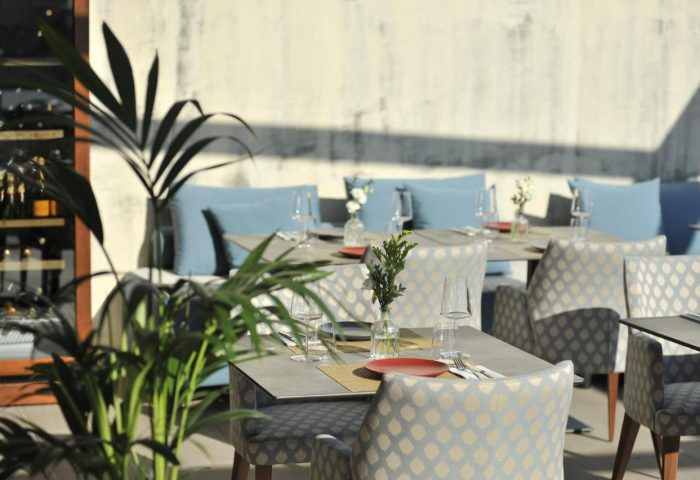 Athenaeum Eridanus Luxury Hotel's outdoor dining area. Gay-friendly hotel with stylish tables, chairs, and plants for a relaxing atmosphere.