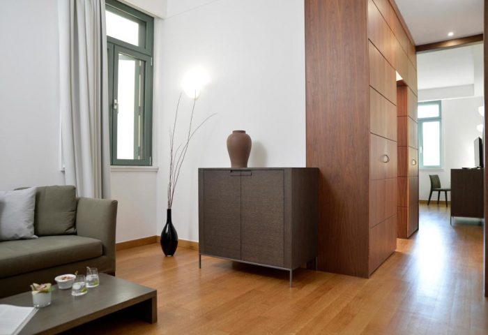 Athenaeum Eridanus Luxury Hotel, Gay-Friendly room. Interior view: couch, table, cabinet, wood floor. Modern design. Gay travel advice.