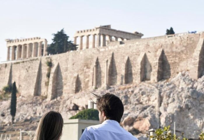 AthensWas Hotel view. Gay couple embraces, overlooking the Acropolis. Gay-Friendly Hotel in Athens, Greece. Romantic travel.