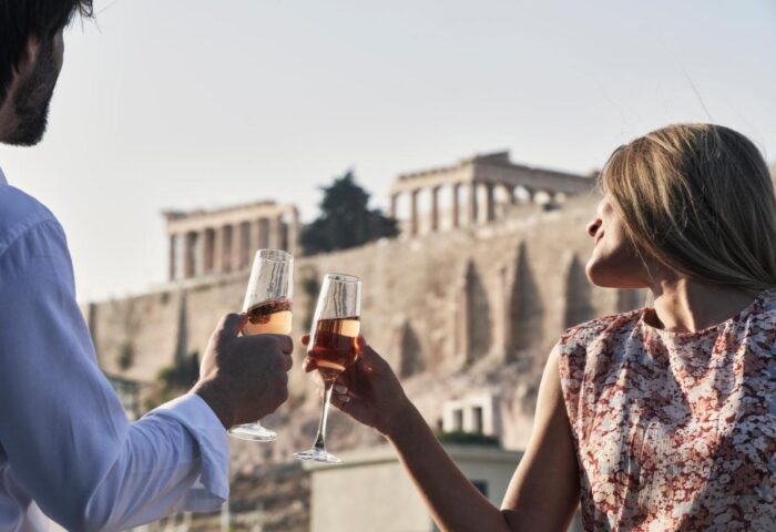 AthensWas Hotel: A couple toasting with champagne, the Acropolis in the background. Gay-friendly hotel in Athens, Greece.