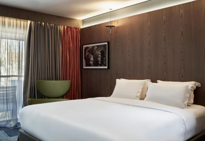 AthensWas Hotel room. Gay-friendly hotel with a bed, chair, curtains, and art. Modern design in Athens.