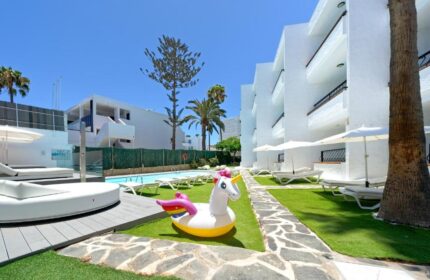 Atlantic Sun Beach gay men only hotel with a unicorn floatie by the pool, sunbeds, and white buildings. Gay-friendly hotel for gay travel.