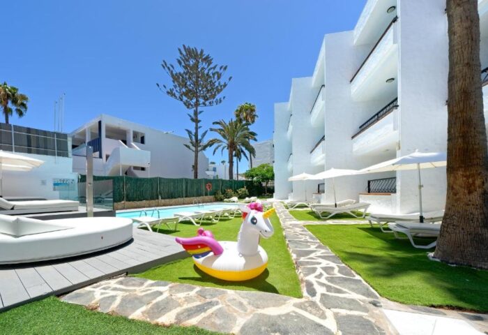 Atlantic Sun Beach gay men only hotel with a unicorn floatie by the pool, sunbeds, and white buildings. Gay-friendly hotel for gay travel.