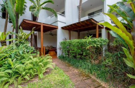 Avani Pattaya Resort garden path. Gay-friendly hotel with lush greenery, wooden pavilions, and tropical plants. Ideal for gay men travelers.